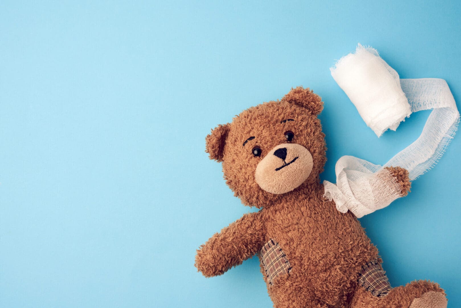 A teddy bear laying next to some diapers