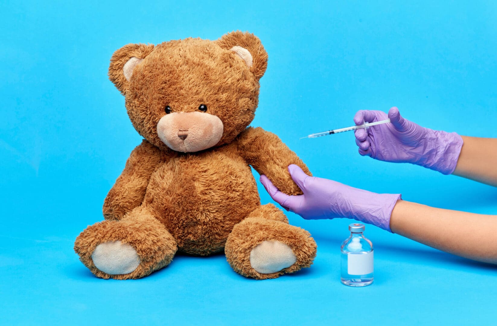 A person is holding a needle in their hand and a teddy bear.